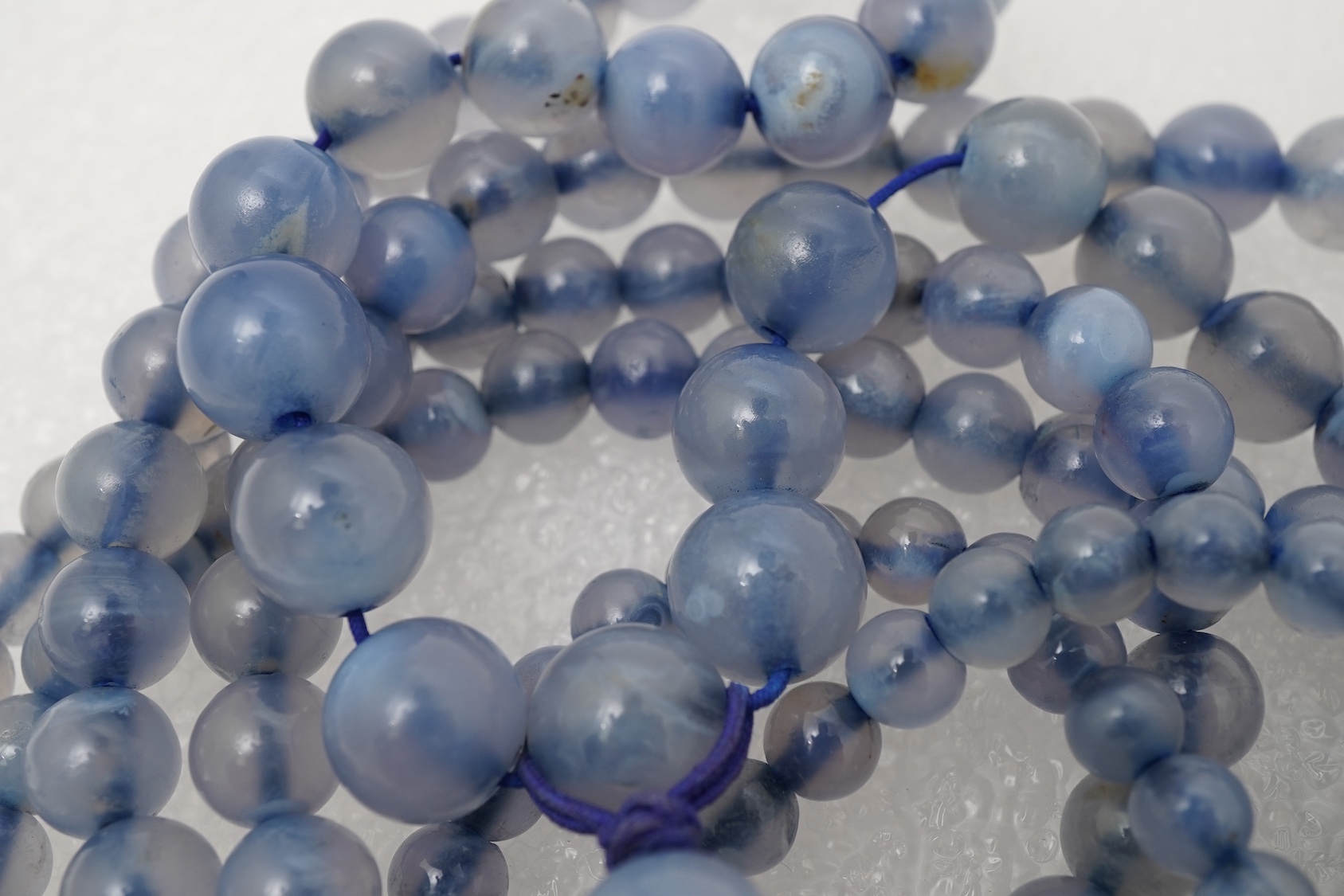 A Chinese jade ‘spirit lock’ plaque, a jadeite bead necklace and a blue quartz bead necklace, 20th century